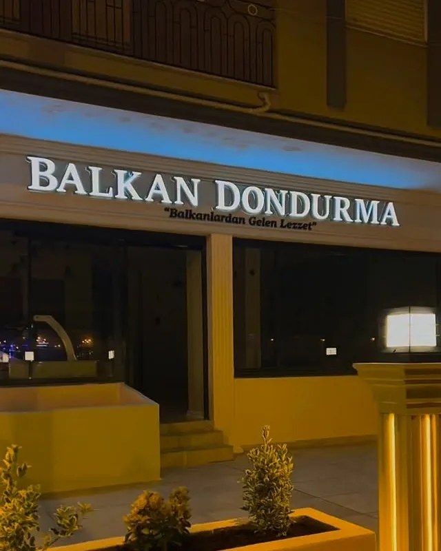 Balkan Dondurma cephesinde mavi arka aydınlatmalı beyaz kutu harf tabela, gece görünümü